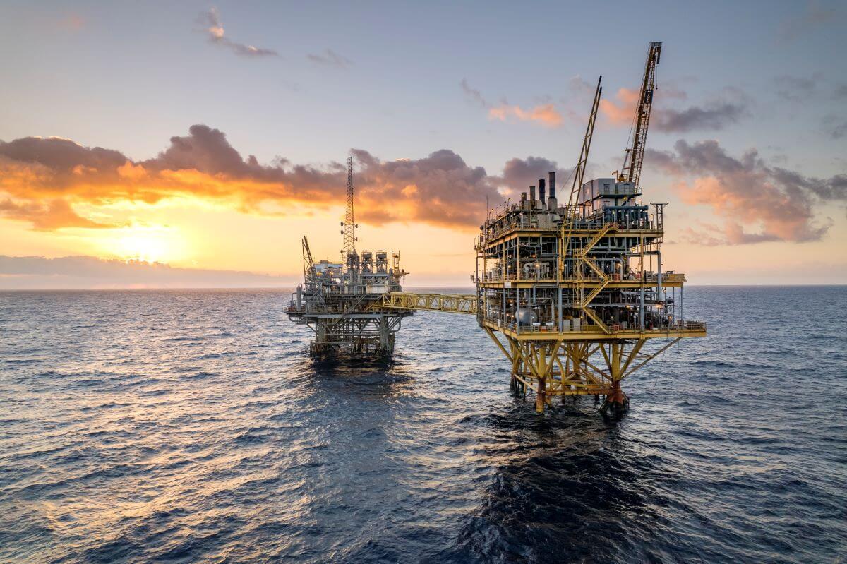 Two offshore platforms in the ocean with sunset in background